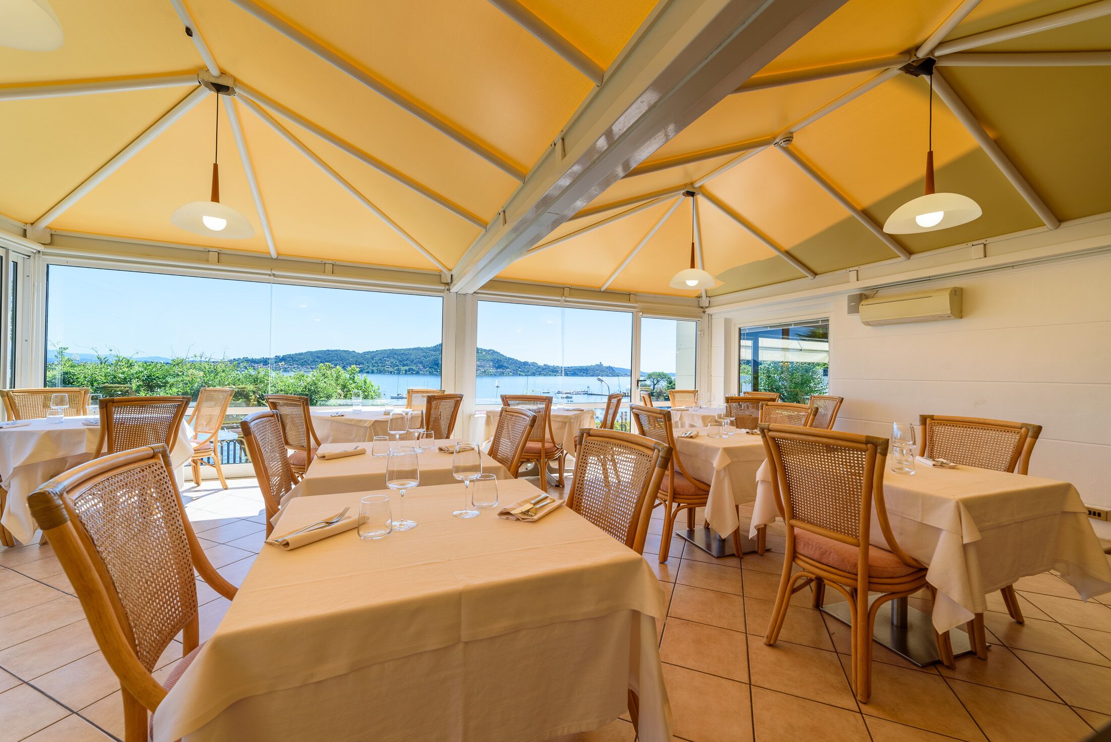 Un restaurante con mesas y sillas, vista al mar y un tejado amarillo.