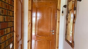 Een houten deur met een messing handvat, een bakstenen muur en een houten vloer.