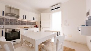 A modern kitchen with white cabinetry, a built-in oven, and a tiled backsplash. - Maruzza Home 101 (Favignana)