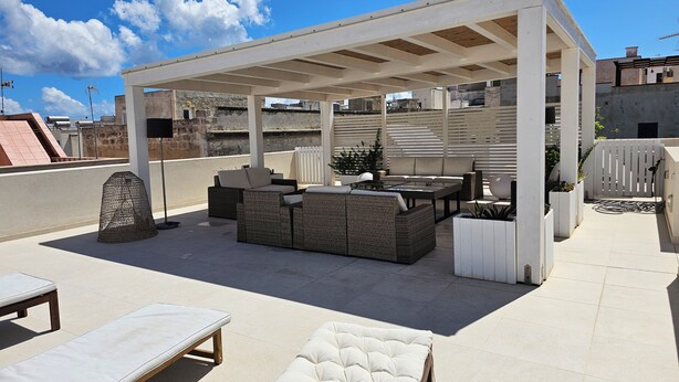 A rooftop patio with outdoor furniture, a pergola, and a view of the cityscape. - Maruzza Home 101 (Favignana)