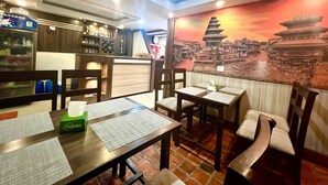 A restaurant interior with wooden tables, chairs, and a mural of a pagoda. - Satkar Boutique Home (Kathmandu)