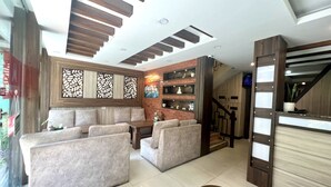 A modern living area with sofas, a coffee table, and a fireplace. There is a staircase leading to another level. - Satkar Boutique Home (Kathmandu)