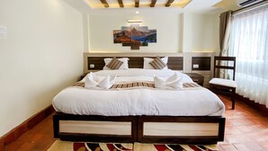 A hotel room with a large bed, wooden headboard, and a painting above the bed. - Satkar Boutique Home (Kathmandu)