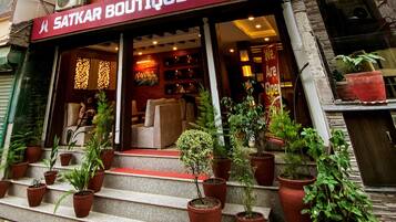 A boutique home with a red sign, outdoor seating, and potted plants.