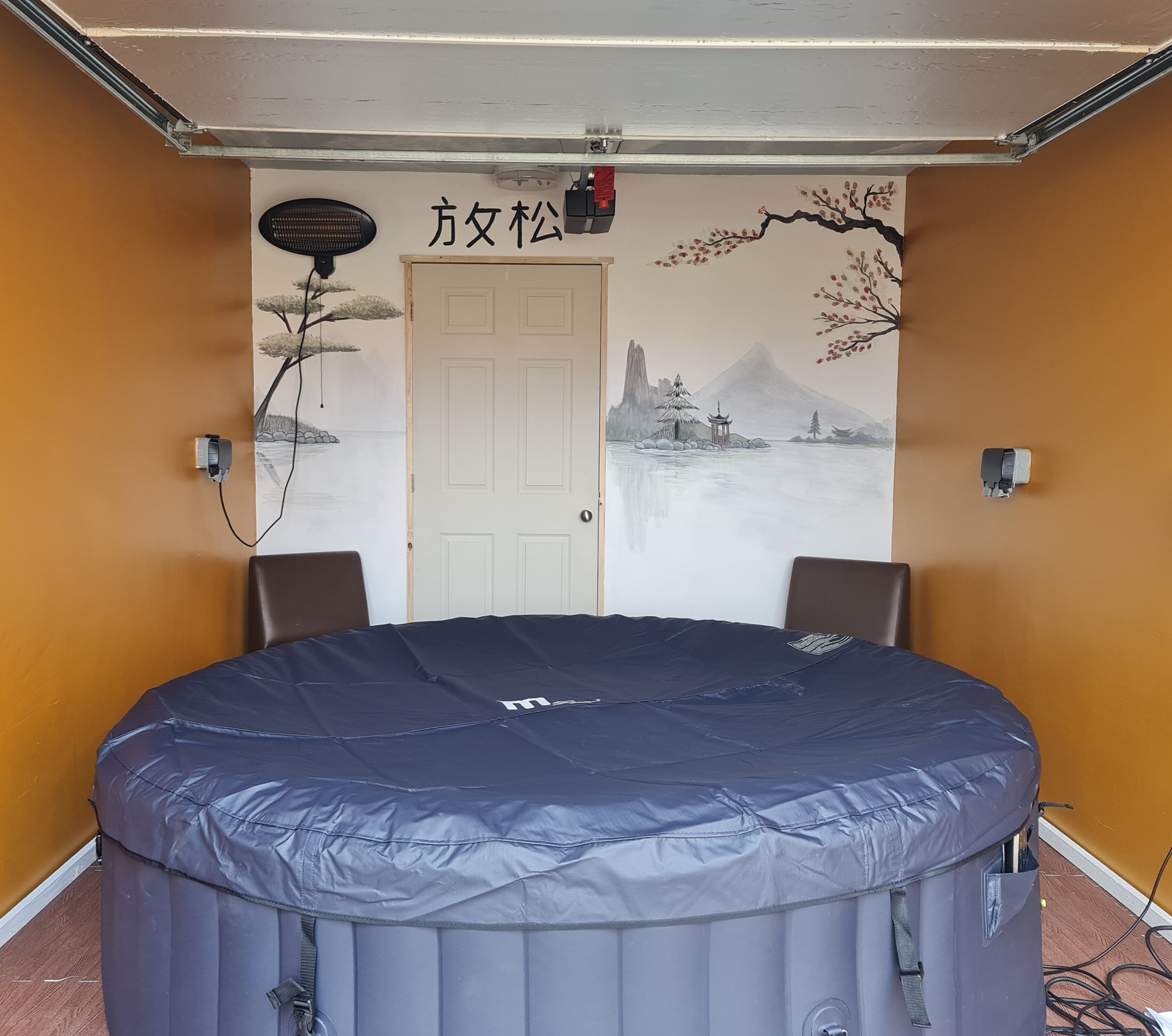 Ein Zimmer mit einem großen Luftbett, einer Tür mit Wandgemälde und zwei Wandlautsprechern.