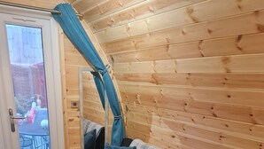 Interior acogedor de una cabaña con un sofá de color oscuro, un tapete de tonos claros y una pared de madera.