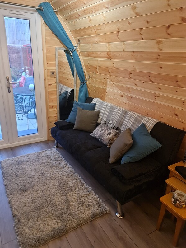 L’intérieur d’un chalet accueillant, avec un canapé aux couleurs foncées, un tapis de couleur claire et un mur en bois.