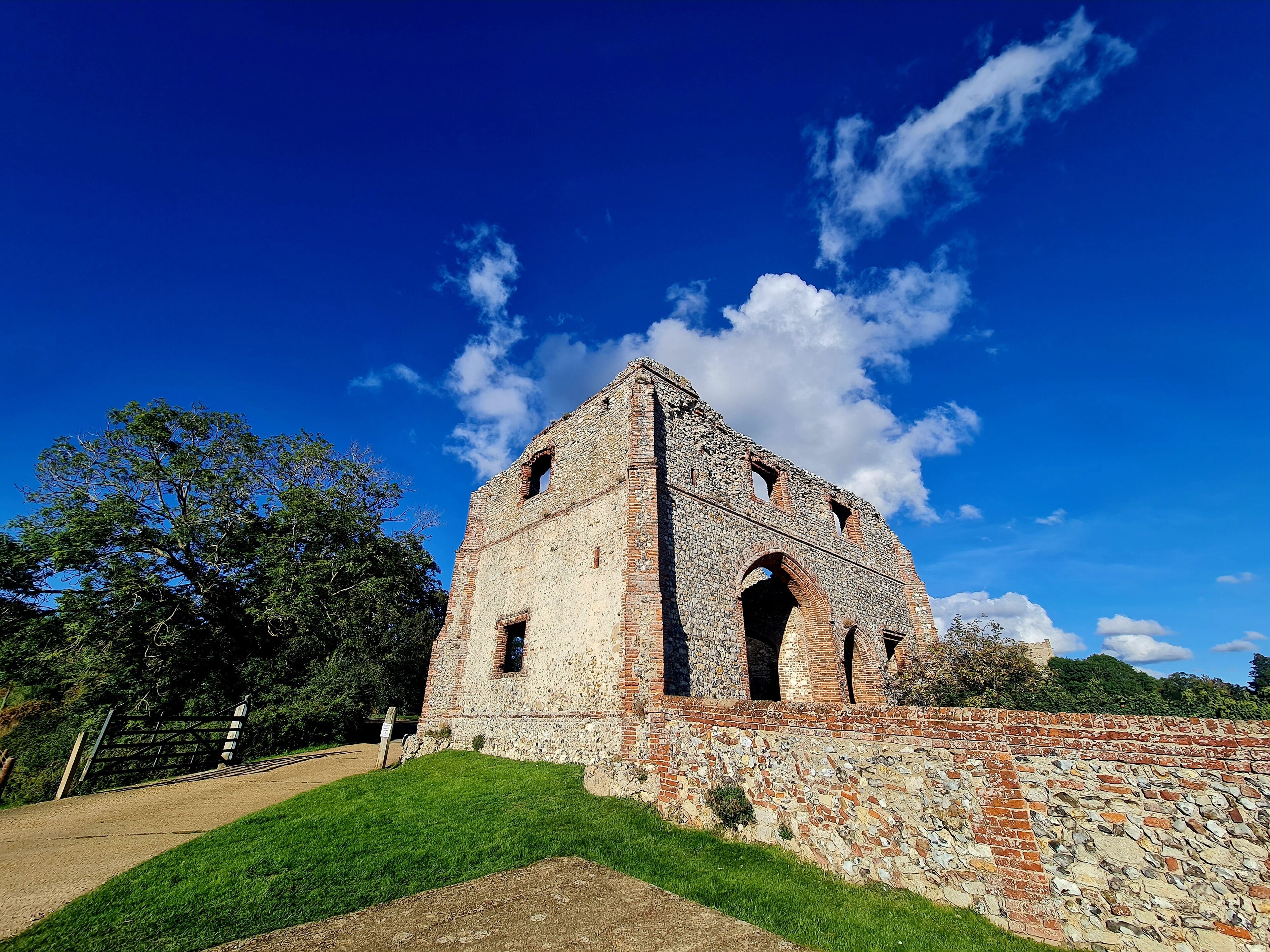 An ancient stone building with arched windows and a grassy foreground.