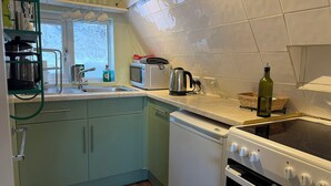 Una cocina con un fregadero, un microondas, un hervidor, un tostador y una estufa.