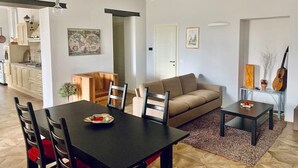 A modern living room with a dining table, sofa, and a small side table. - Apartment in the countryside (Piemonte)