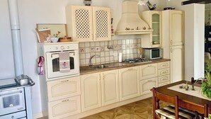 A kitchen with a stove, oven, sink, cabinets, and a dining table with chairs. - Apartment in the countryside (Piemonte)