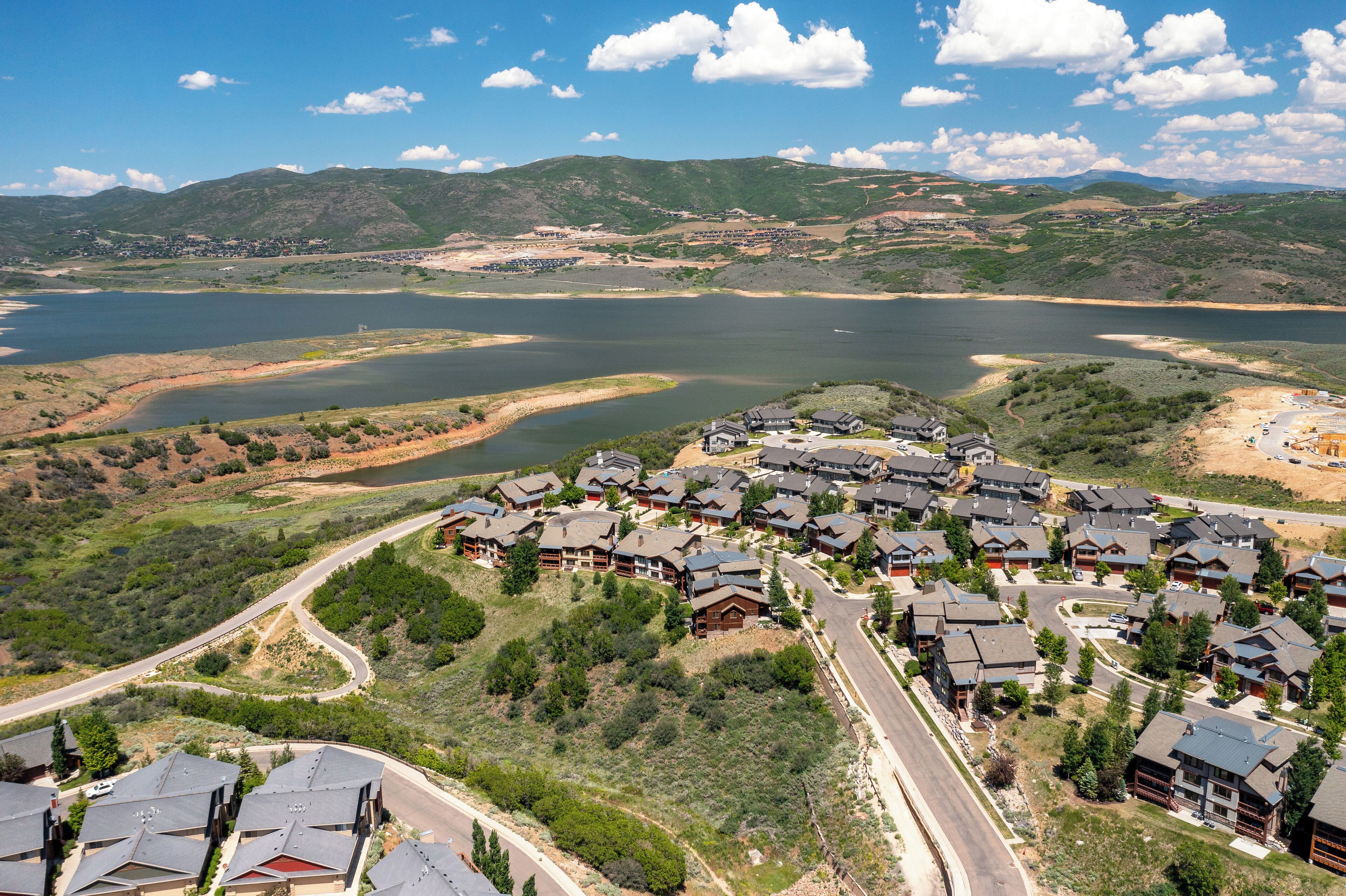A residential area with houses near a lake, surrounded by hills.