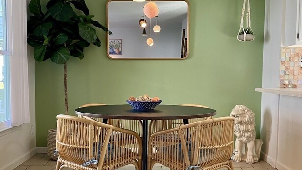 A dining area with a round table, four wicker chairs, a mirror, and a hanging light fixture. - Great First Floor Condo! (Greenville)