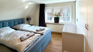 A bedroom with two beds, a window with a view, a radiator, and a cabinet.
