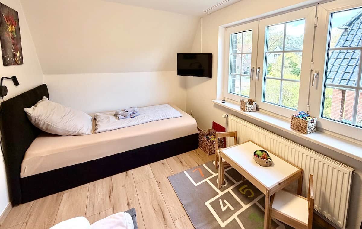 Ein Schlafzimmer mit einem Bett, einem Fernseher, einem Fenster mit Aussicht, einem Tisch mit einem Korb und einer Heizung.