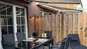 An outdoor patio with a table and chairs, a wooden fence, and a brick wall.