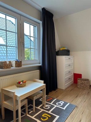 A child's playroom with a window, a radiator, a white dresser, and a play mat. - Maila Vacation Home (Varel)