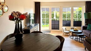 A living room with a dining table, chairs, a sofa, and a television.