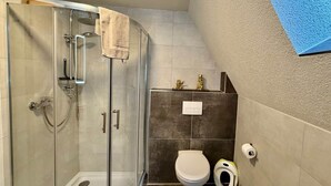 A bathroom with a glass-enclosed shower, a toilet, and a bidet.