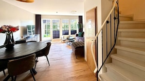 A modern interior with a dining area, sofa, and staircase.