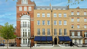 A row of brick townhouses with bay windows and a central building with a distinctive corner turret. - Beaverbrook Town House (London)