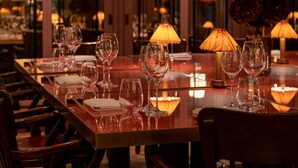 A restaurant with a long table set for dining, multiple wine glasses, and table lamps. - Beaverbrook Town House (London)