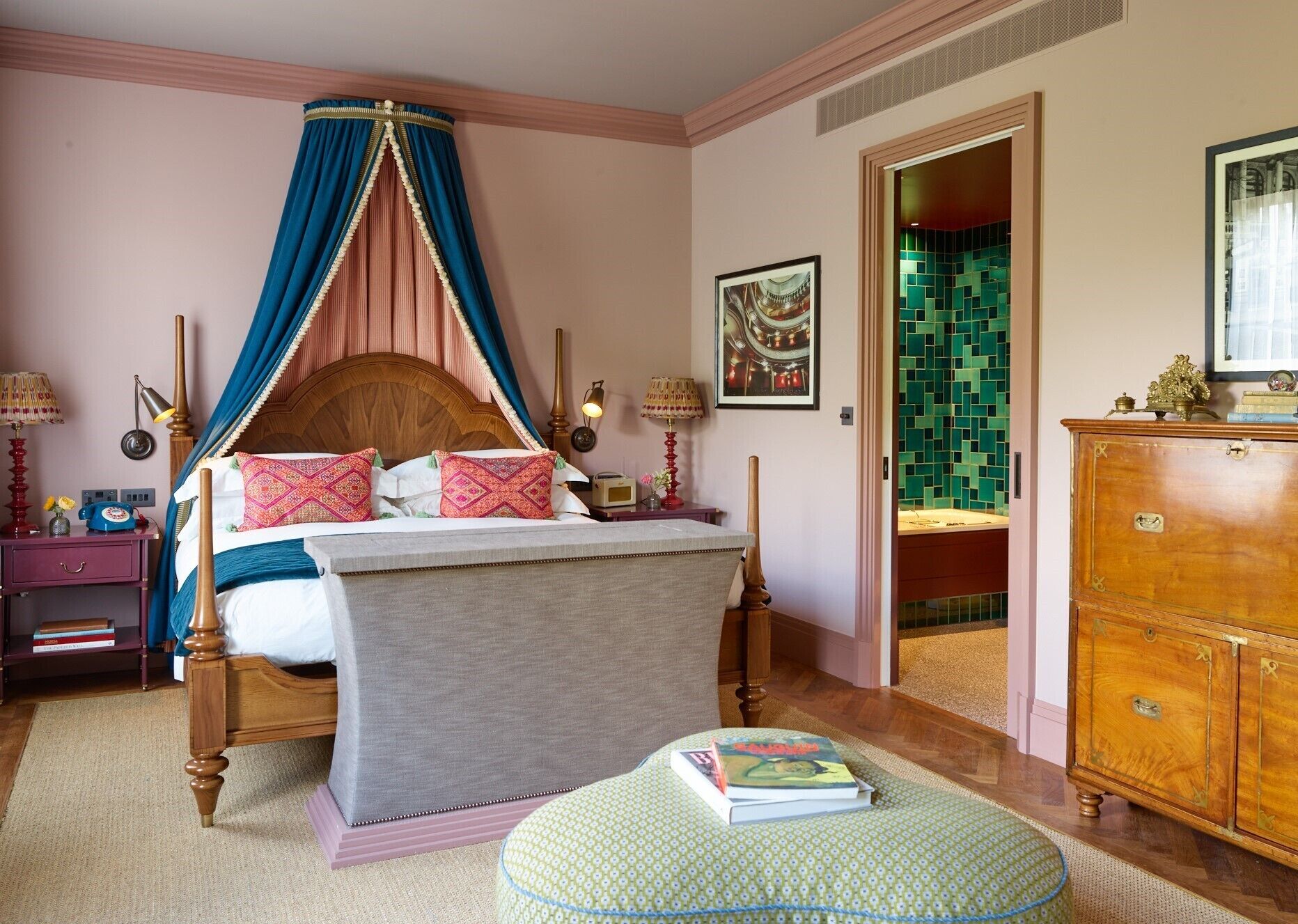 A bedroom with a four-poster bed, a wooden dresser, and a green ottoman.