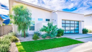 A modern house with a large garage, a well-maintained lawn, and a variety of plants. - Indian Wells Luxury - Private Pool & Shuffleboard! (Indian Wells)
