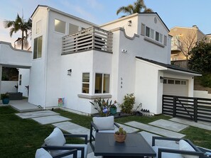 A modern two-story house with a white exterior, a balcony with a railing, and a garage. - Modern Dream Home - Fire Pit, Grill, Large Yard & AC (Encinitas)