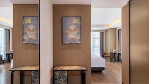 Una habitación de hotel moderna con un panel de pared de madera, una cama grande, un escritorio con cubierta de mármol y dos obras de arte enmarcadas.