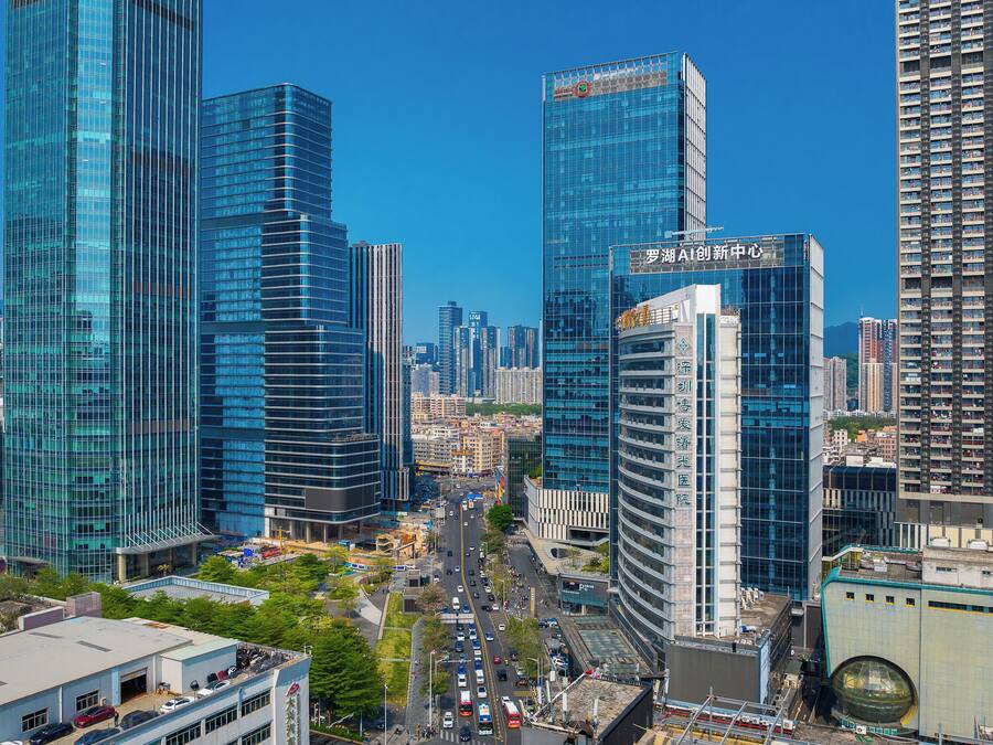 Un paisaje urbano con modernos rascacielos, una calle concurrida y cielos azules despejados.