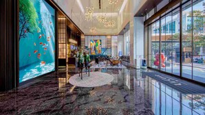 Un lobby amplio con una gran pantalla digital de acuario, candelabros modernos y vistas a la calle a través de amplios ventanales.