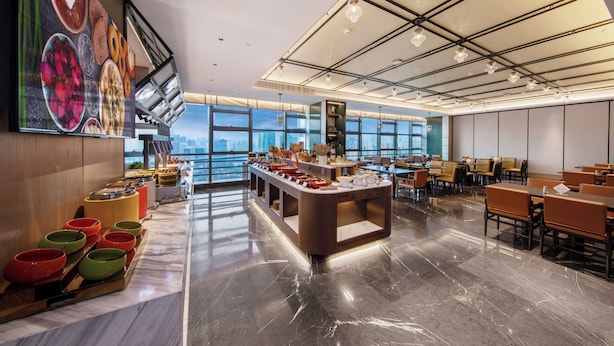 Un comedor moderno con mesas de buffet, ventanas amplias y vistas a la ciudad.