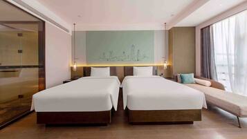 Habitación de hotel con dos camas, un ventanal grande y un mural con vista a la ciudad.
