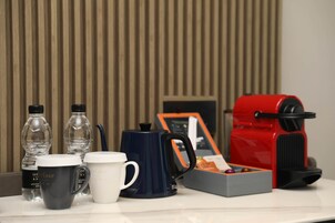 Uma mesa com uma cafeteira, duas canecas e duas garrafas de água.