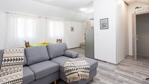 A modern living room with a grey sofa, a patterned throw blanket, and a dining area with a green table. - Centrally-located two-bedroom apartment w/sunny terrace Marina IV. (Split)