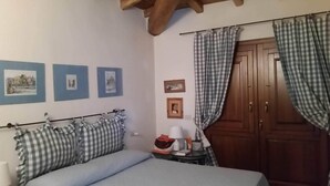 Een slaapkamer met een bed, nachtkastje, lamp en een kledingkast. Er hangen drie ingelijste foto's aan de muur.
