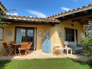 Eine Terrasse mit Tisch, Stühlen, einem blauen Schrank und einer Couch.