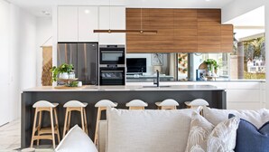 A modern kitchen with white cabinetry, a central island with bar stools, and a view of the outdoors.