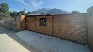 Une porte en bois ornée d’un logo, un mur de pierre et une montagne en arrière-plan.