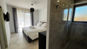 Une chambre d’hôtel moderne dotée d’un grand lit, d’un espace douche et offrant une vue sur l’extérieur.