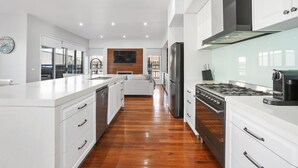 A modern kitchen with white cabinetry, a stainless steel refrigerator, and a gas stove.