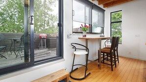 Una cocina moderna con techo de madera, una zona de comedor con un banco y una silla, y un amplio ventanal con vistas a una terraza.