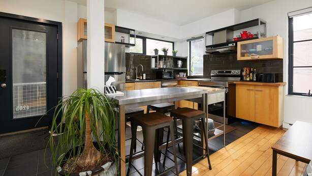Una cocina moderna con una isla central, taburetes de bar y electrodomésticos integrados.