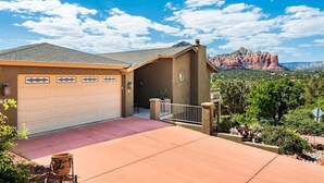 A residential house with a garage, a driveway, and a view of red rock formations. - Breathtaking Unblockable Red Rock Views, 3BD sleeps 7, West Sedona! (Sedona)