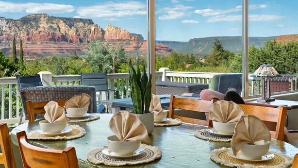 A dining table set with bowls and napkins, overlooking a scenic view of red rock formations. - Breathtaking Unblockable Red Rock Views, 3BD sleeps 7, West Sedona! (Sedona)