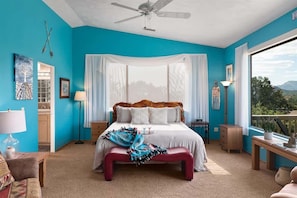A bedroom with a bed, a ceiling fan, a window with curtains, a bedside table, and a view of the outdoors. - Breathtaking Unblockable Red Rock Views! - Breatht (Sedona)