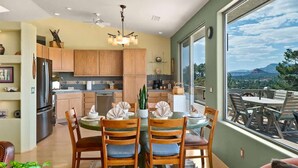 A modern kitchen with wooden cabinets, a dining area with a round table and chairs, and a large window offering a view of the outdoors. - Breathtaking Unblockable Red Rock Views, 3BD sleeps 7, West Sedona! (Sedona)