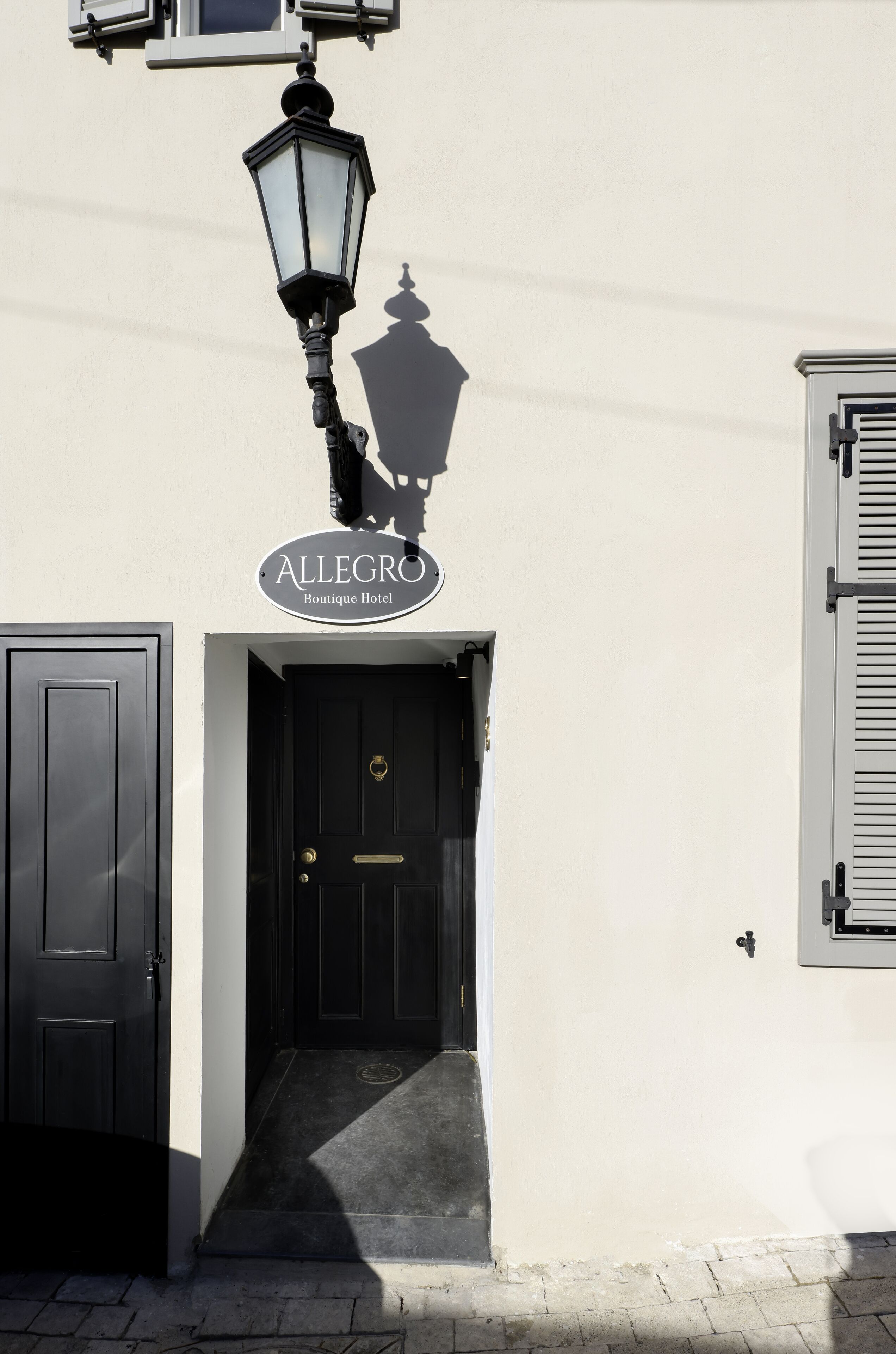 Entrada de hotel con puerta negra, un cartel sobre la puerta y una farola.