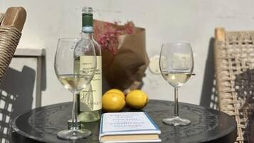 A small round table with two wine glasses, a bottle of white wine, and two lemons. A book is also on the table.
